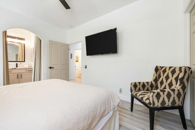 bedroom featuring ceiling fan, ensuite bath, and light wood-type flooring