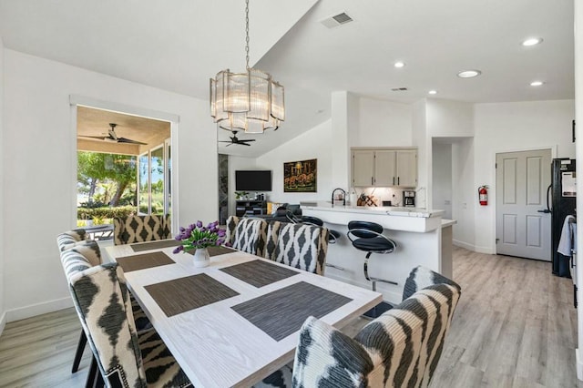 dining area featuring ceiling fan with notable chandelier, light hardwood / wood-style floors, and lofted ceiling