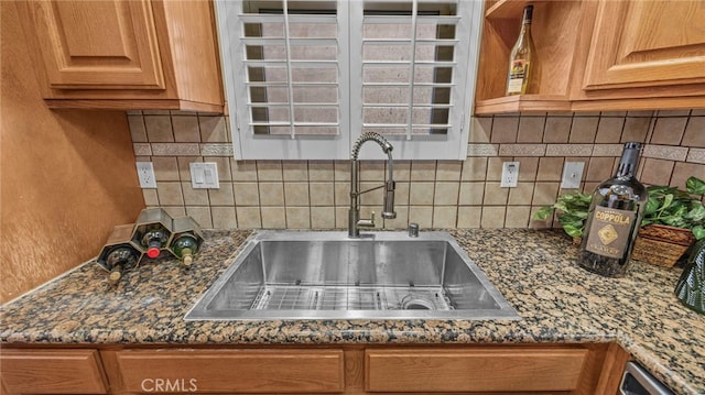 kitchen with decorative backsplash, dark stone countertops, and sink