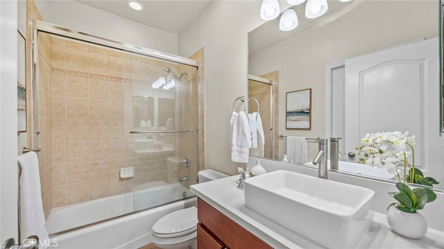 full bathroom featuring toilet, combined bath / shower with glass door, and vanity