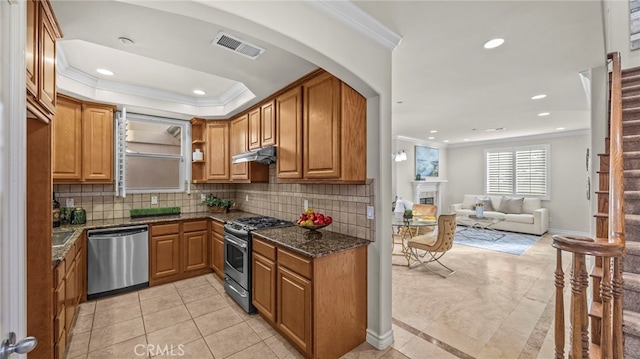 kitchen featuring stainless steel appliances, dark stone countertops, backsplash, ornamental molding, and light tile patterned floors