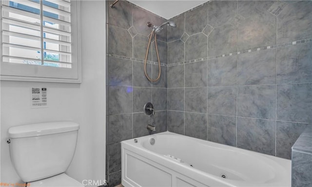 bathroom featuring toilet and tiled shower / bath