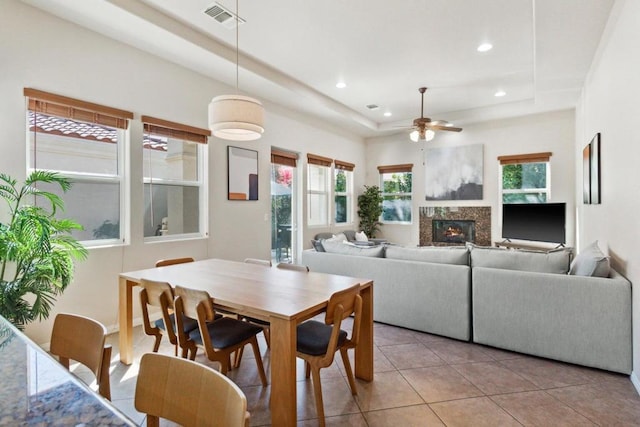 dining room featuring ceiling fan, light tile patterned flooring, and a tray ceiling