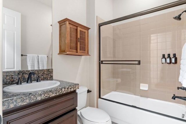 full bathroom with decorative backsplash, toilet, vanity, and combined bath / shower with glass door