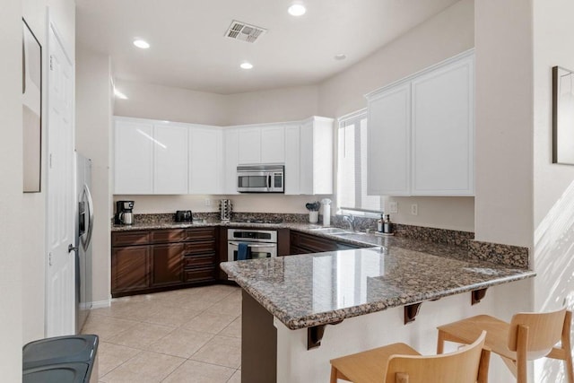 kitchen featuring white cabinets, appliances with stainless steel finishes, sink, stone countertops, and kitchen peninsula