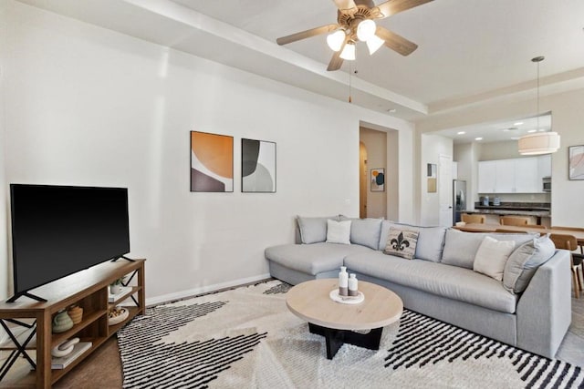 living room featuring ceiling fan and a raised ceiling