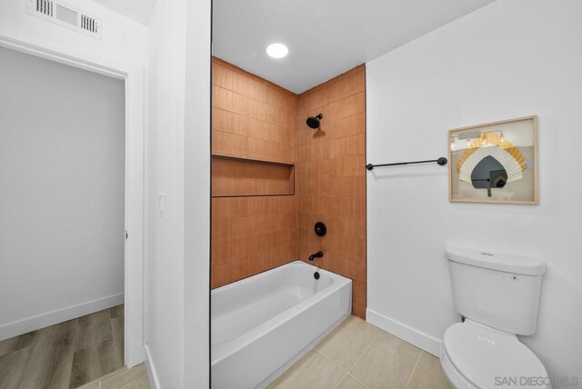 bathroom with tiled shower / bath, tile patterned floors, and toilet