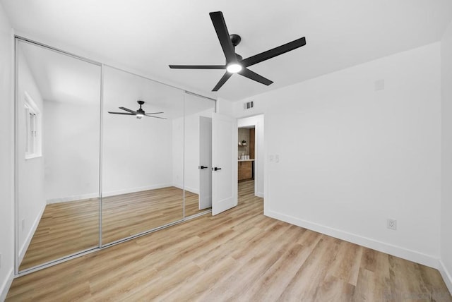 unfurnished bedroom featuring light hardwood / wood-style floors, ceiling fan, and a closet