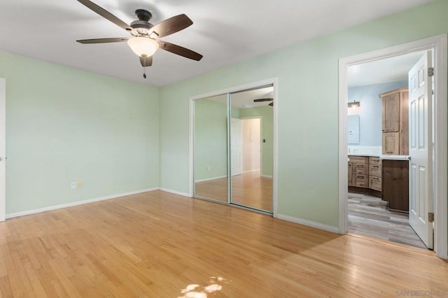 unfurnished bedroom with ceiling fan, a closet, connected bathroom, and light hardwood / wood-style floors