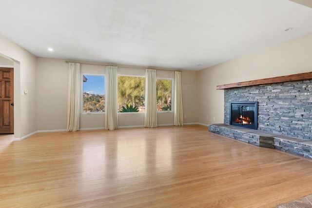 unfurnished living room with a stone fireplace and light wood-type flooring