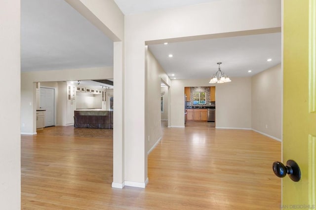 hallway featuring an inviting chandelier and light hardwood / wood-style flooring