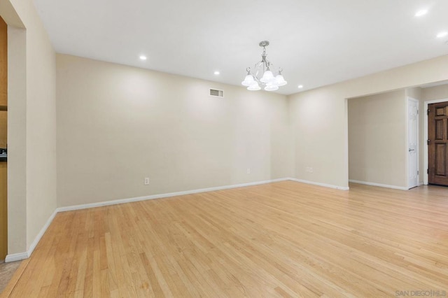 empty room with an inviting chandelier and light hardwood / wood-style floors