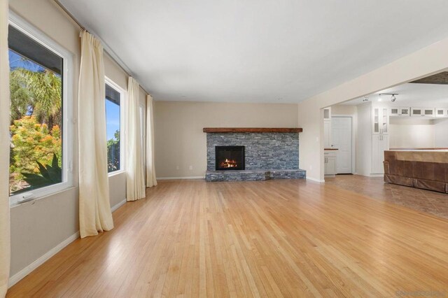 unfurnished living room featuring a stone fireplace and light hardwood / wood-style floors