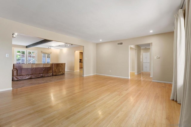 unfurnished living room with light hardwood / wood-style floors and beam ceiling