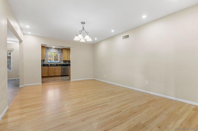 empty room with an inviting chandelier, light hardwood / wood-style flooring, and sink