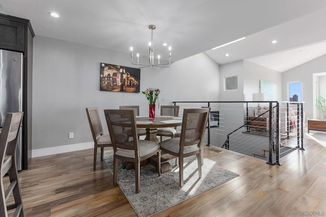 dining area featuring vaulted ceiling, an inviting chandelier, and hardwood / wood-style floors