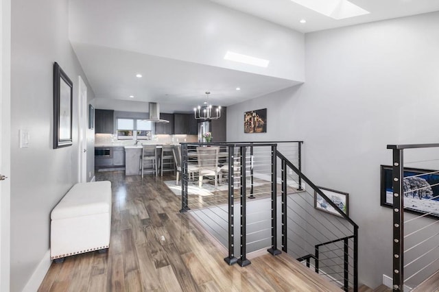 stairway featuring a skylight, an inviting chandelier, and hardwood / wood-style flooring