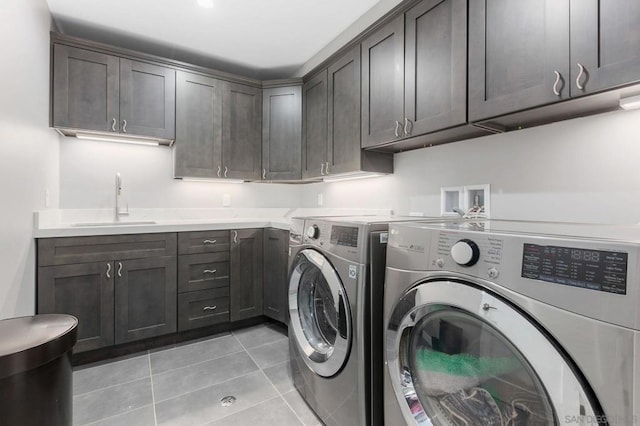 washroom featuring cabinets, sink, light tile patterned flooring, and washing machine and clothes dryer