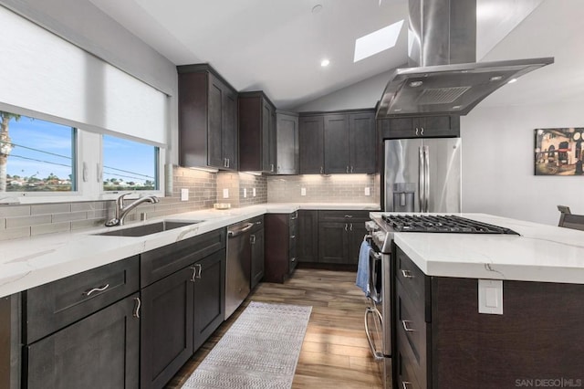 kitchen with appliances with stainless steel finishes, extractor fan, sink, light wood-type flooring, and lofted ceiling with skylight