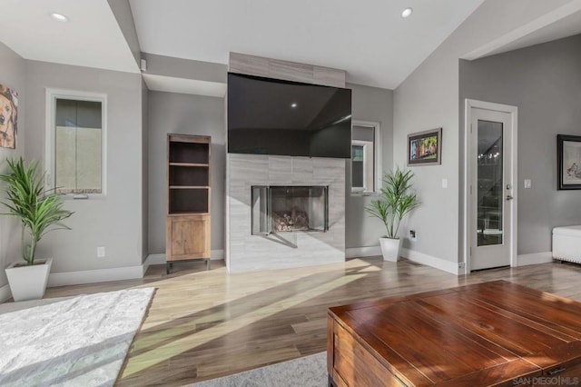 living room featuring lofted ceiling, a fireplace, and hardwood / wood-style floors