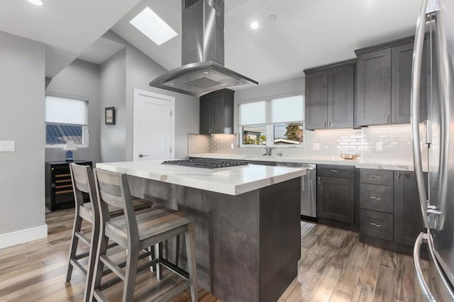 kitchen featuring hardwood / wood-style floors, island range hood, stainless steel appliances, and a kitchen island