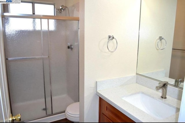 bathroom featuring toilet, a shower with door, and vanity