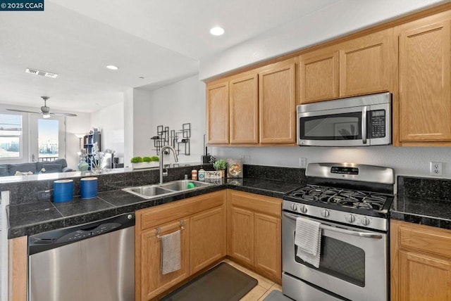 kitchen featuring appliances with stainless steel finishes, sink, light tile patterned floors, ceiling fan, and kitchen peninsula