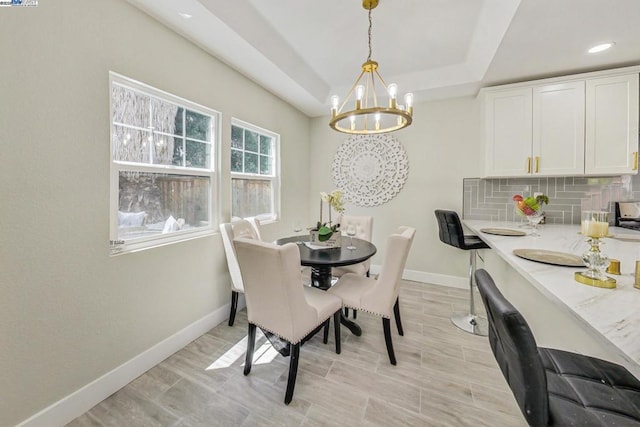 dining space featuring a tray ceiling and a chandelier