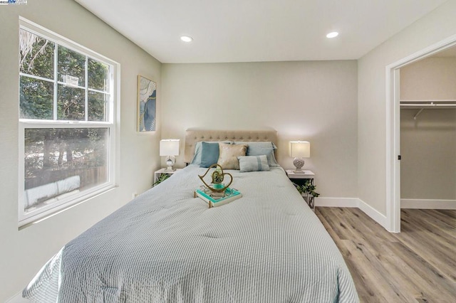 bedroom with a walk in closet and light hardwood / wood-style floors