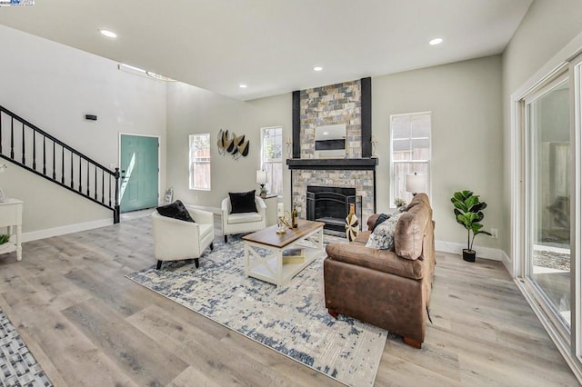 living room with a stone fireplace and light hardwood / wood-style flooring