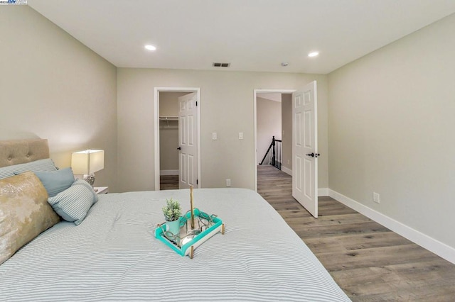 bedroom with hardwood / wood-style flooring and a walk in closet