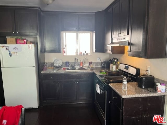 kitchen featuring light stone countertops, sink, white refrigerator, and range with electric stovetop