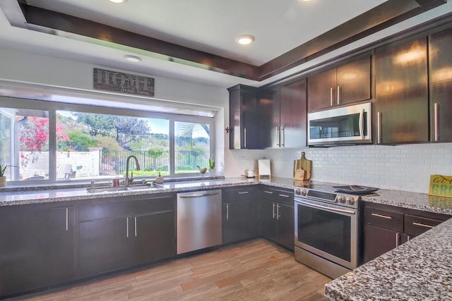 kitchen featuring decorative backsplash, sink, dark brown cabinetry, appliances with stainless steel finishes, and stone countertops