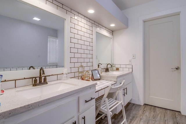 bathroom featuring hardwood / wood-style flooring, vanity, and tasteful backsplash