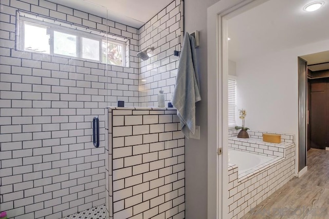 bathroom featuring shower with separate bathtub and wood-type flooring