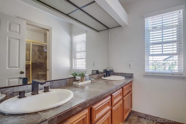 bathroom with a healthy amount of sunlight, walk in shower, and vanity