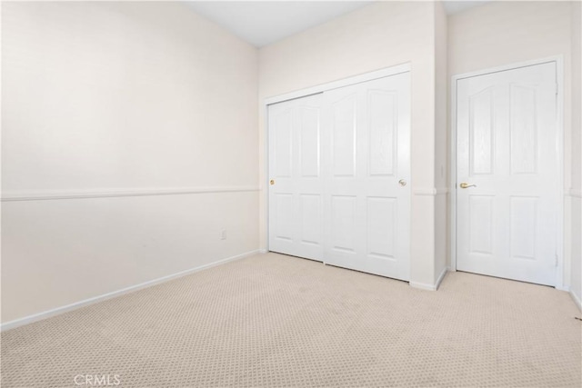 unfurnished bedroom featuring light carpet and a closet