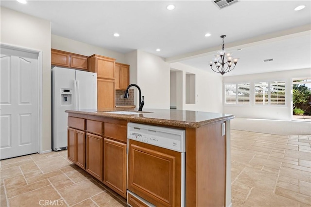 kitchen with sink, dishwasher, white fridge with ice dispenser, a center island with sink, and decorative light fixtures