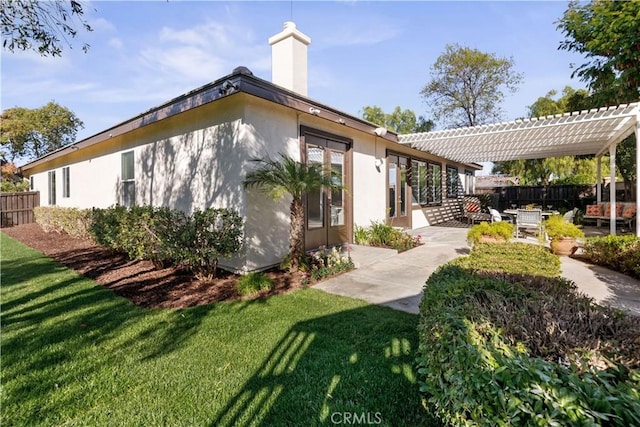 back of property featuring a lawn, a patio area, and a pergola