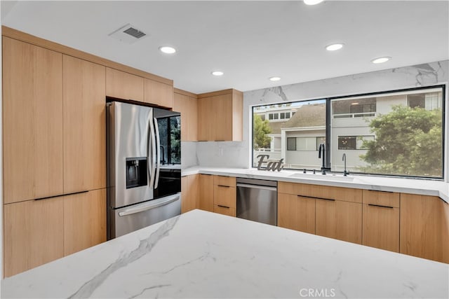 kitchen with light stone countertops, sink, light brown cabinets, and stainless steel appliances