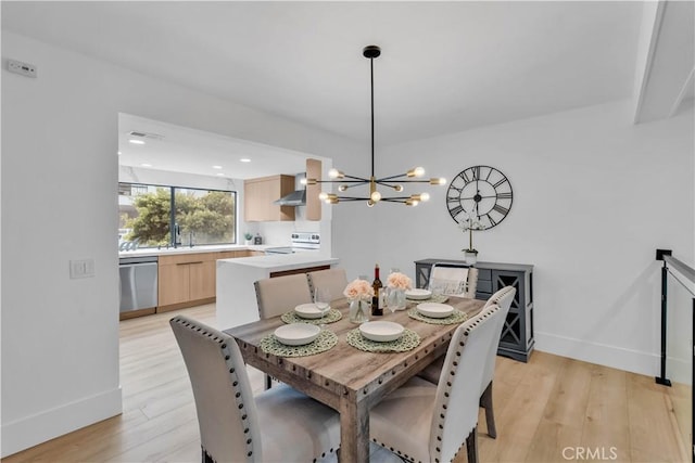 dining area with a notable chandelier, sink, and light hardwood / wood-style floors