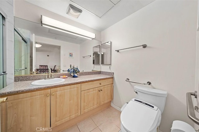 bathroom with toilet, tile patterned flooring, a shower with door, and vanity