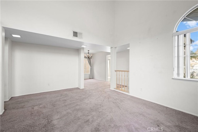 carpeted spare room featuring an inviting chandelier