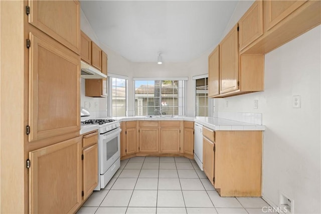 kitchen with tile countertops, sink, white appliances, light tile patterned floors, and light brown cabinetry