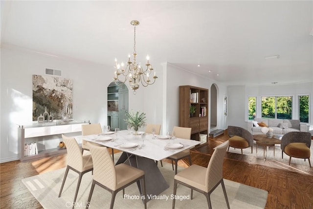 dining area featuring crown molding, a chandelier, and hardwood / wood-style floors