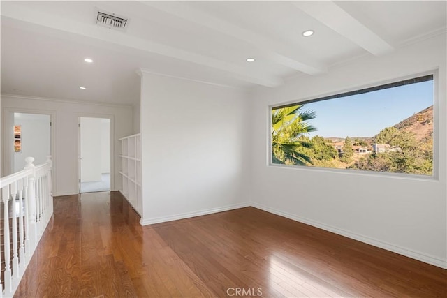 spare room with ornamental molding, wood-type flooring, and beam ceiling