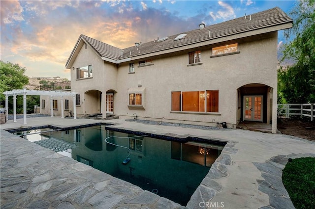 back house at dusk with a pergola, a patio area, and french doors