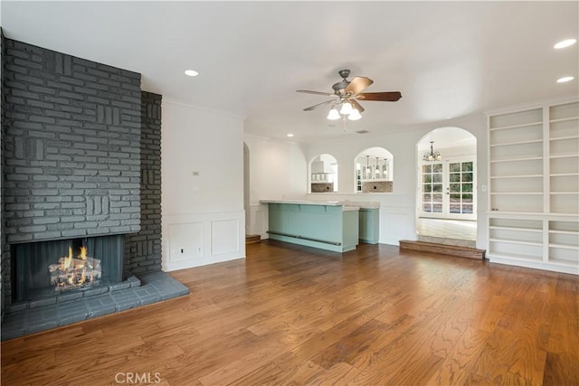 unfurnished living room with hardwood / wood-style flooring, a fireplace, ornamental molding, and ceiling fan