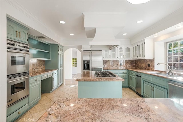 kitchen with appliances with stainless steel finishes, backsplash, custom range hood, white cabinets, and a kitchen island