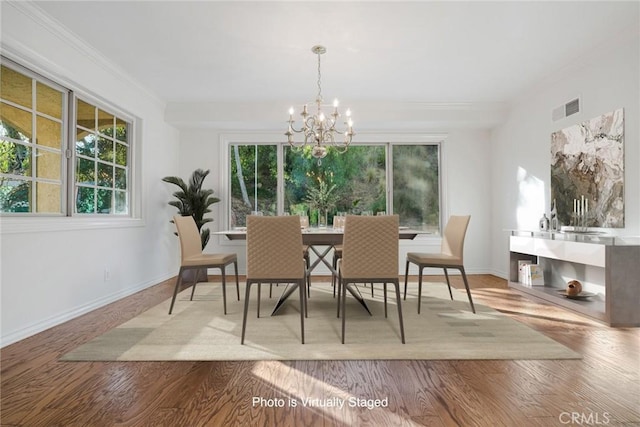 dining space with an inviting chandelier, crown molding, and light hardwood / wood-style floors